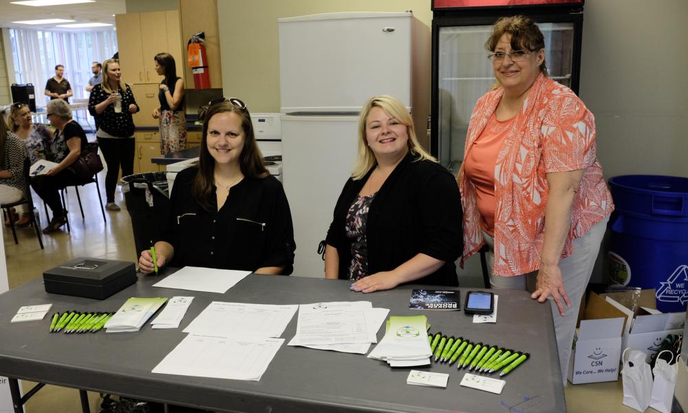 photo of 3 board members sitting at a table taking registrations